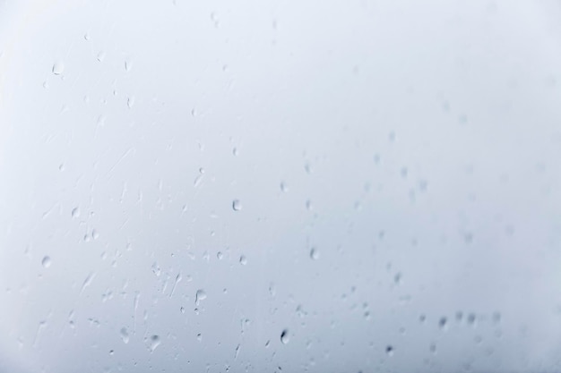 Regentropfen auf Glas Selektiver Fokus Trauriges bewölktes Wetter Graublauer Hintergrund Platz für Text