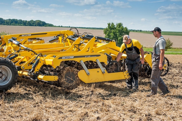 REGIÓN DE TERNOPIL, UCRANIA - 10 de agosto de 2021: el hombre inspecciona el tractor cultivador en la demostración de maquinaria agrícola, exposición de la empresa Lan Bednar