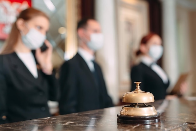 Registro en el hotel. recepcionista en el mostrador del hotel con máscaras médicas como precaución contra el virus. Mujer joven en un viaje de negocios haciendo el check-in en el hotel