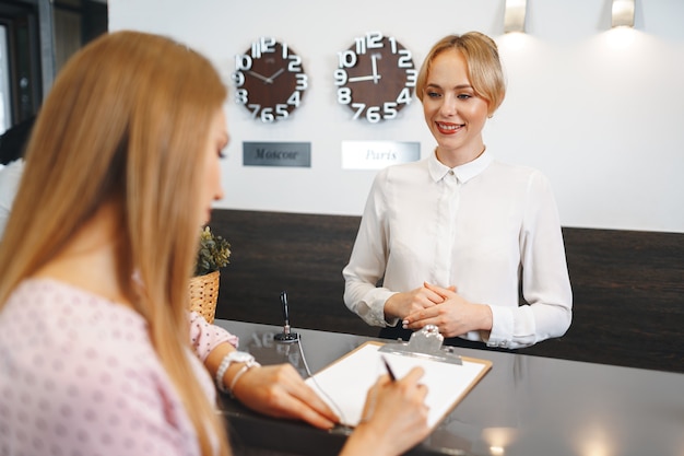 Registro de huéspedes de hotel mujer rubia en la recepción del hotel