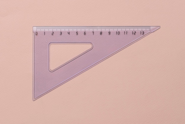 Foto una regla triangular cuadrada transparente sobre útiles escolares de fondo pastel