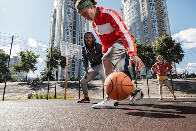 Reglas de baloncesto. Jóvenes deportistas mirando la pelota mientras tienen un partido de baloncesto