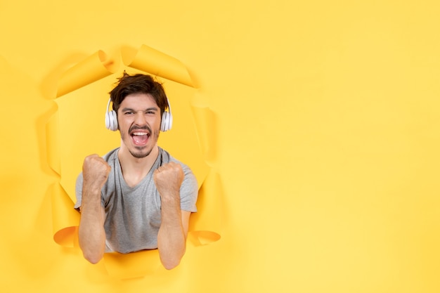 Regocijo macho joven en auriculares sobre papel amarillo rasgado sonido de audio de ultrasonido de fondo