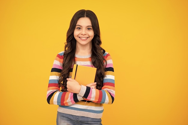 Regreso a la escuela Colegiala adolescente con libro listo para aprender Niñas de la escuela sobre fondo de estudio amarillo aislado Adolescente feliz emociones positivas y sonrientes de niña adolescente