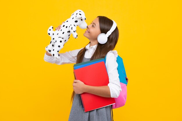 Regreso a la escuela Colegiala adolescente sostenga el libro con el juguete listo para aprender Niños de la escuela sobre fondo de estudio amarillo aislado Niña feliz emociones positivas y sonrientes