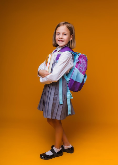 Regreso a la escuela Una colegiala con una mochila escolar sobre un fondo de estudio aislado El concepto de escuela y educación Una adolescente con uniforme escolar