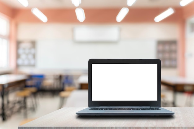 Regreso a la escuela Computadora portátil abierta con pantalla blanca en blanco en el escritorio del maestro en el espacio de copia del auditorio de la escuela