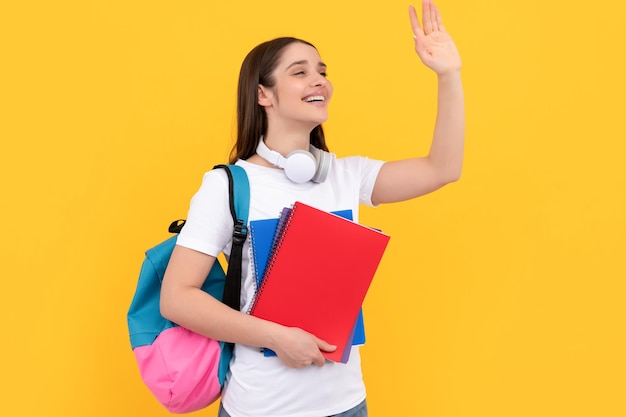 Regreso a la escuela concepto de educación moderna estudiante feliz sostener cuaderno saludando hola niña sosteniendo cuaderno sobre fondo amarillo profesor privado con cuadernos y auriculares