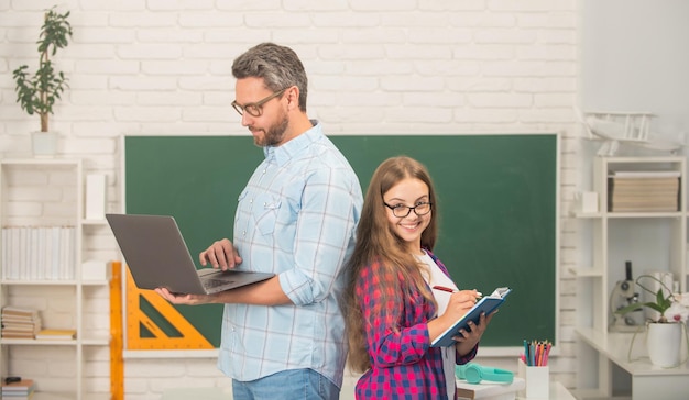 Regreso a la escuela educación infantil alumno sonriente y tutor con computadora