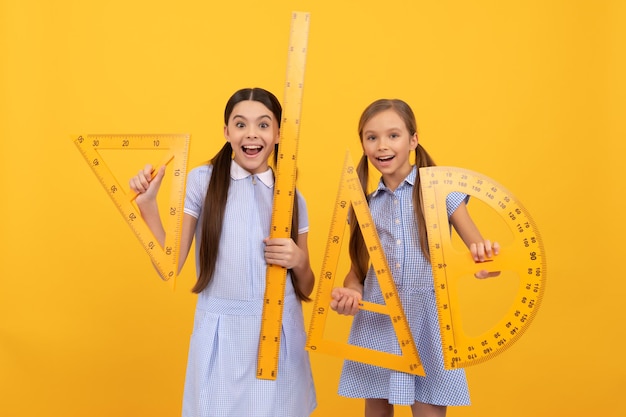 El regreso a la escuela está aquí Colegialas felices sostienen herramientas geométricas Lección de geometría de regreso a la escuela Mejoramos la sabiduría con la educación