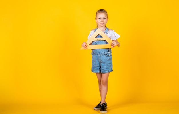 Regreso a la escuela infancia feliz niño lindo sobre fondo amarillo disciplinas de tallo de educación hermosa niña adolescente con regla de triángulo niño como herramienta de medición de matemáticas matemáticas haciendo su tarea