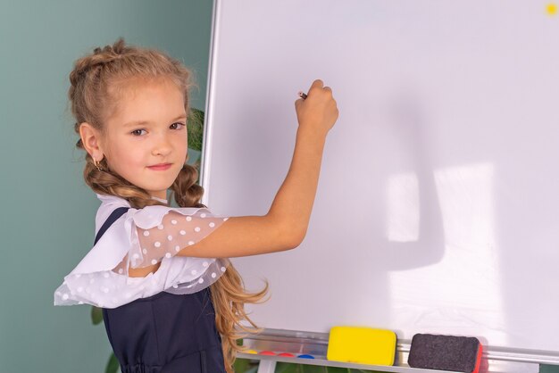 Regreso a la escuela linda chica en la escuela con libros cerca de la pizarra