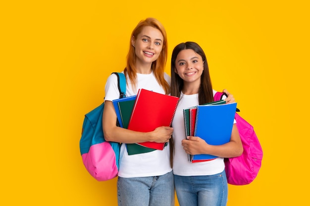 Regreso a la escuela Madre e hija adolescente con mochila Adolescentes estudiantes sobre fondo amarillo aislado Mamá e hijo van a la escuela