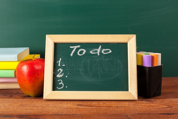 Regreso a la escuela: manzana y libros con lápices y pizarra