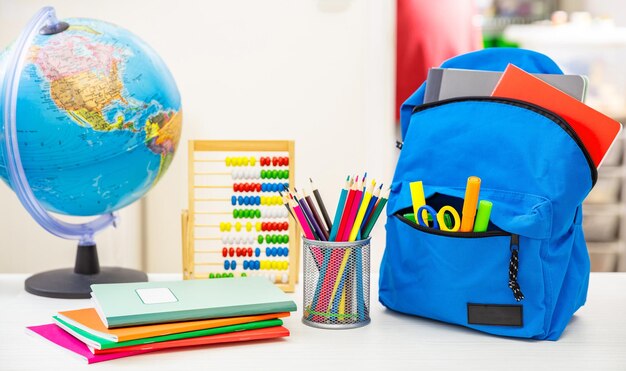 Regreso a la escuela Mochila y suministros para estudiantes en el escritorio blanco