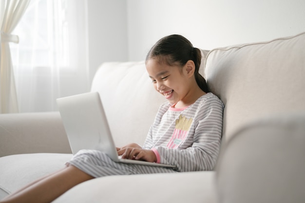 Regreso a la escuela, niña asiática que usa su computadora portátil