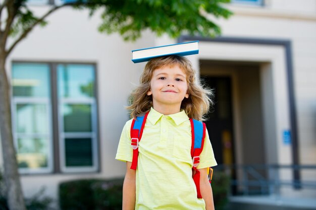 Regreso a la escuela niño divertido en gafas cerca de niño de la escuela primaria con libro y ba