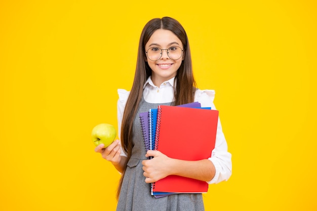 Regreso a la escuela Niño de la escuela adolescente estudiante niña con mochila mantenga manzana y libro aislado en amarillo