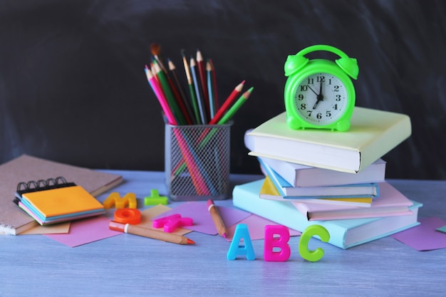 Regreso a la escuela, pila de libros, reloj, papelería sobre la mesa