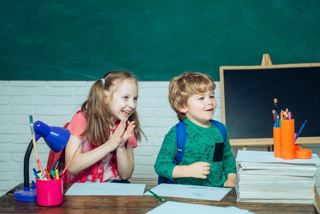 Regreso a la escuela y tiempo feliz Primera vez en la escuela Niña y niño con expresión de cara feliz cerca del escritorio con útiles escolares