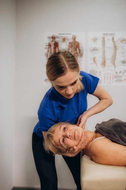 un rehabilitador masajea el cuello de una anciana