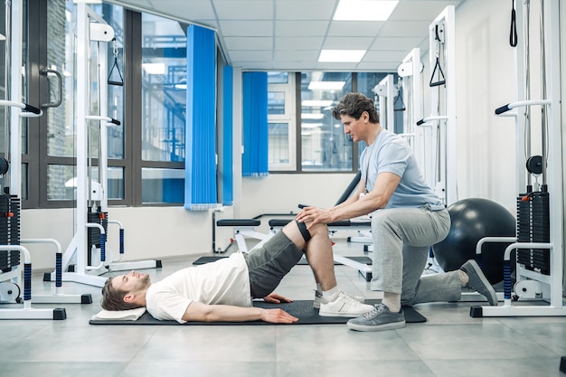 Rehabilitation Erfahrener Instruktor unterstützt einen Mann bei einem Rehabilitationstraining