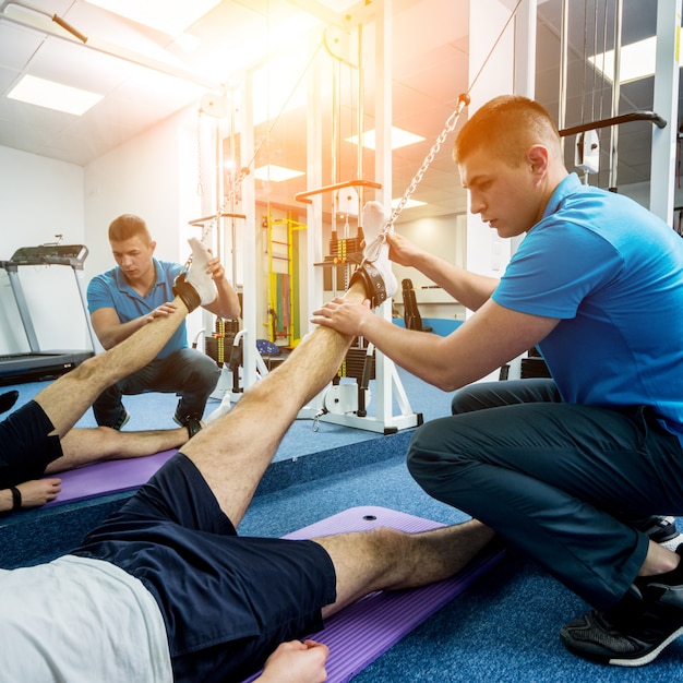 Rehabilitationstherapie. Junger Mann, der Übungen auf Matte macht