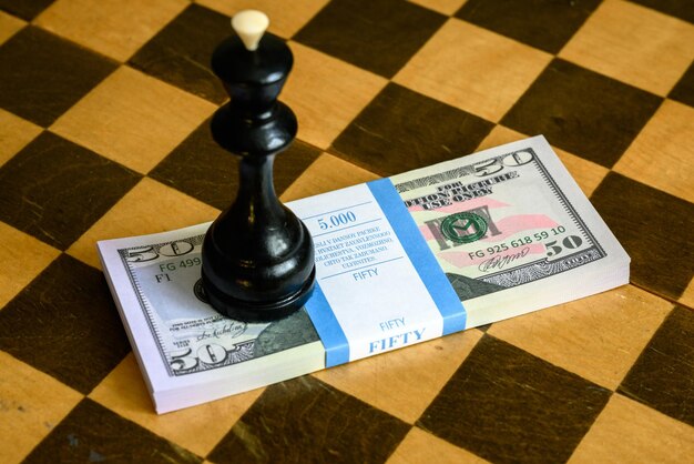 Rei do xadrez e notas de dólar empilhadas no tabuleiro de xadrez