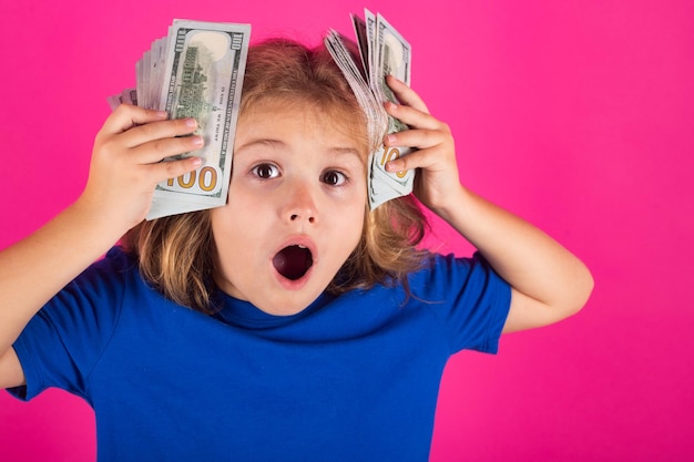 Reiches aufgeregtes Kind mit Dollar Lotterie-Cashback gewinnt großes Geld isoliert auf rosarotem Hintergrund