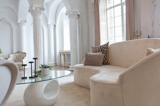 Reichhaltiges luxuriöses Interieur eines gemütlichen Zimmers mit modernen stilvollen Möbeln und Flügel, dekoriert mit barocken Säulen und Stuck an den Wänden