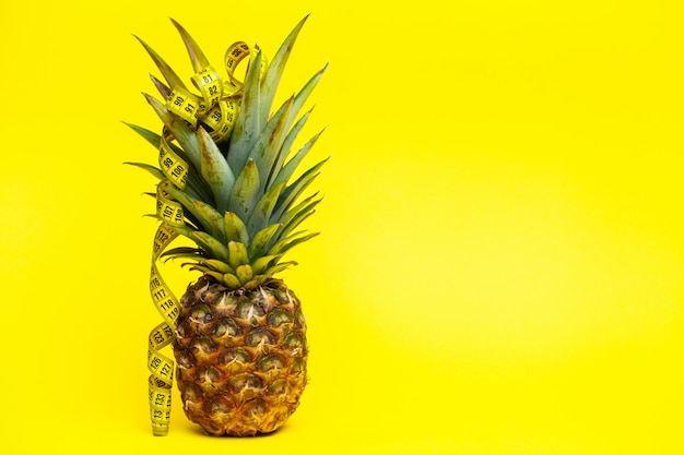 Reife Ananas mit Maßband auf gelb.