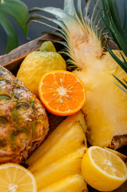 Reife Ananas. Tropische Früchte Mix Holzkiste. Mandarinen Orangen Ananas Zitronen. Geschnittener tropischer Zitrusvitaminnachtisch als Sommerhintergrund. Hochwertiges Archivfoto