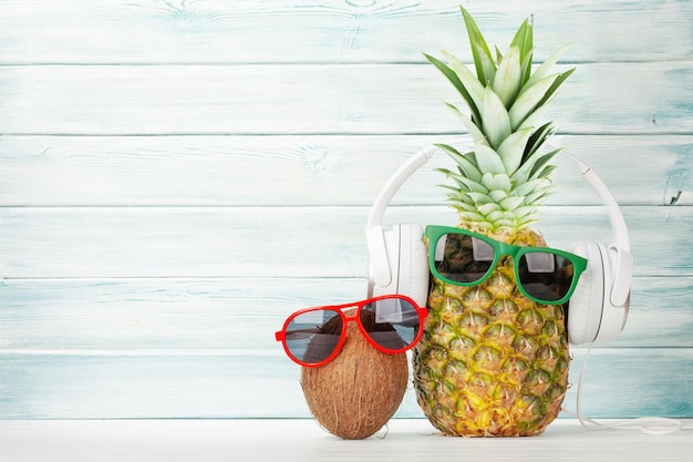 Reife Ananas und Kokosnuss mit Sonnenbrille und Kopfhörern