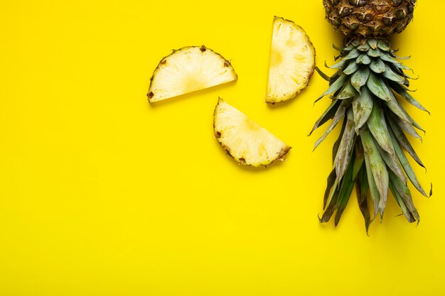 Reife Ananasscheiben, Ananas mit Laub auf gelbem Grund. Ansicht von oben, flach.