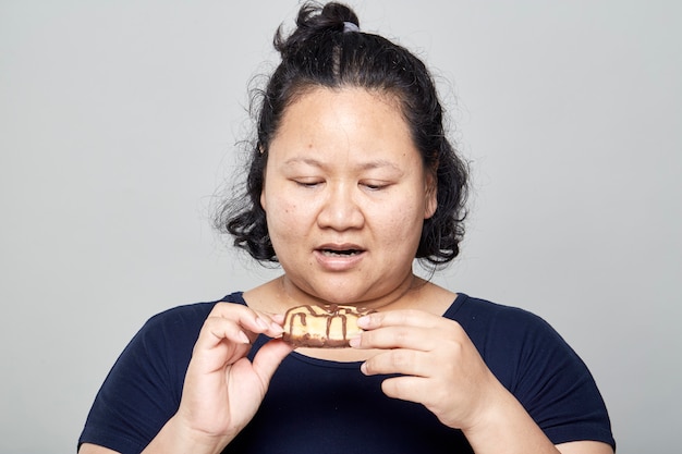 Reife asiatische Frau isst Donuts