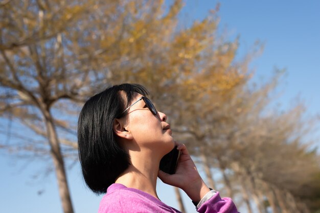 Reife asiatische Schönheit sprechen auf dem Handy im Freien