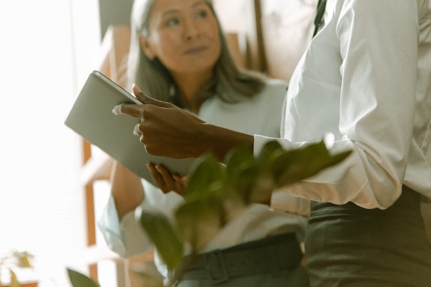 Reife asiatische und junge afrikanische Geschäftsfrauen arbeiten zusammen. Nahaufnahme der weiblichen Hände halten