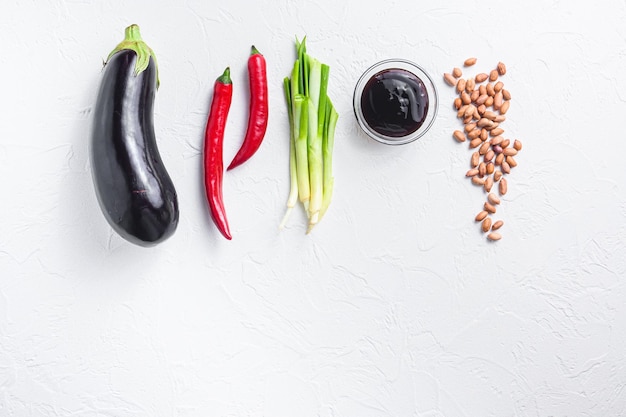 Reife Auberginenbestandteile zum Kochen oder Grillen von Paprika-Auberginen-Sauce-Nüssen auf Draufsichtraum des weißen Hintergrundes für Text