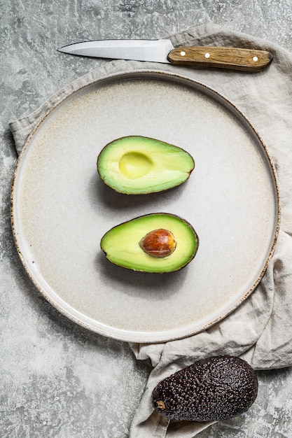 Foto reife avocadohälften auf einer lehmplatte. ansicht von oben