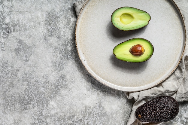 Reife Avocadohälften auf einer Lehmplatte.