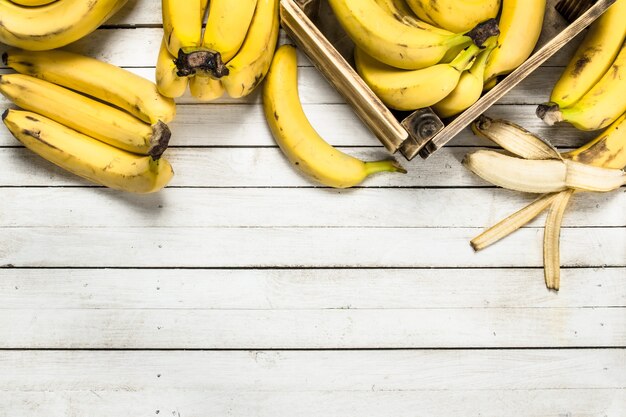 Reife Bananen in einer Schachtel auf weißem Holztisch.