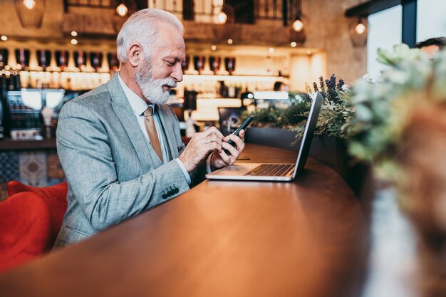 Reife Bartgeschäftsleute, die im modernen Café am Laptop arbeiten.