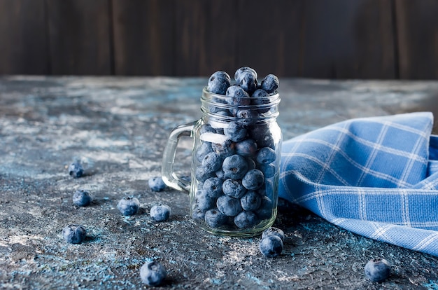 Reife Beeren Blaubeeren im Glas auf einem dunklen Betonhintergrund