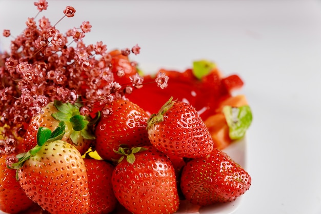 Reife Bio-Erdbeeren mit Blumen auf weißer Oberfläche