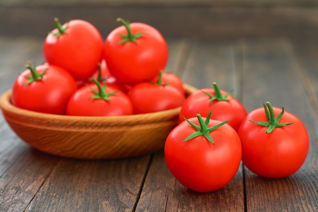 Reife Bio-Tomaten in einer Holzschale auf einem rustikalen Tisch.