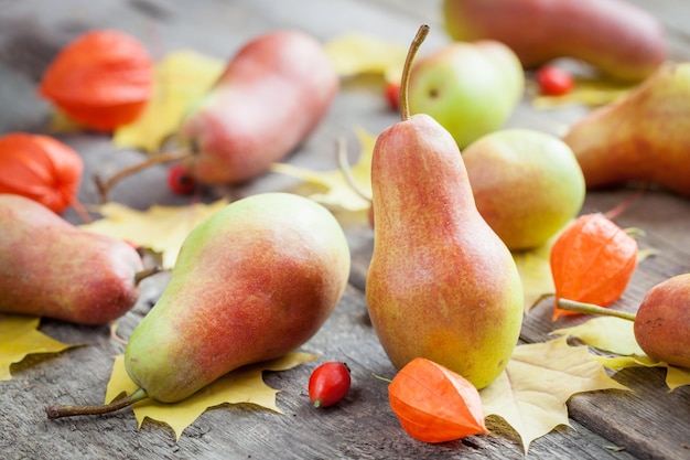 Reife Birnen auf Holztisch mit Herbstlaub und Beeren Selektiver Fokus