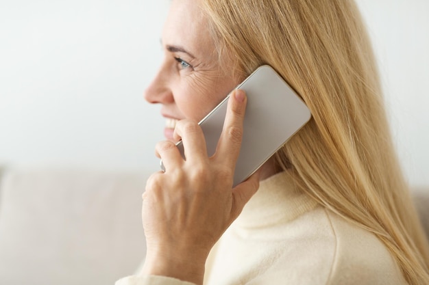 Foto reife blonde frau, die am telefon seitenansicht spricht