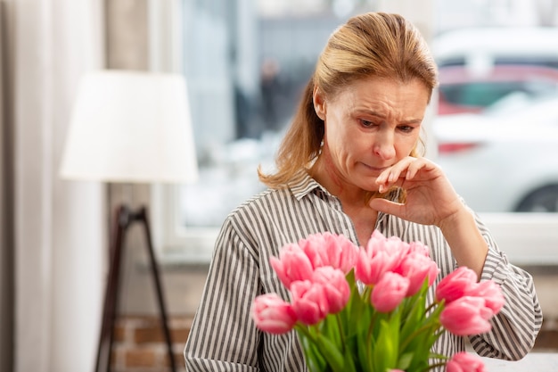 Reife blonde Frau, die empfindlich auf Blumen reagiert, während sie Allergie hat