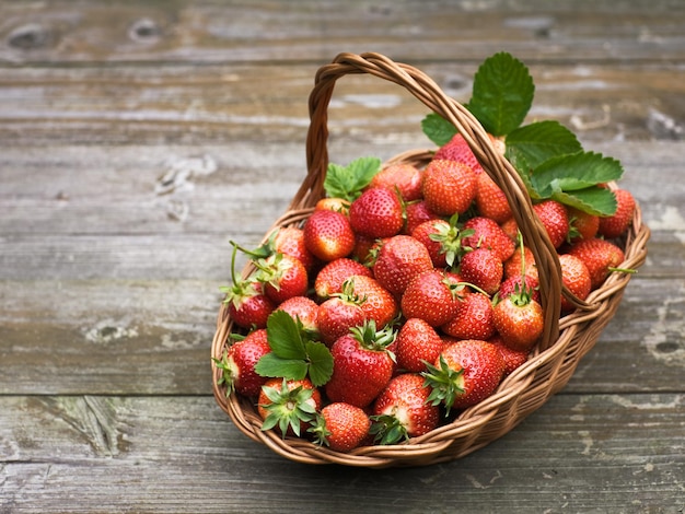 Reife Erdbeeren in einem Korb auf altem Holztisch