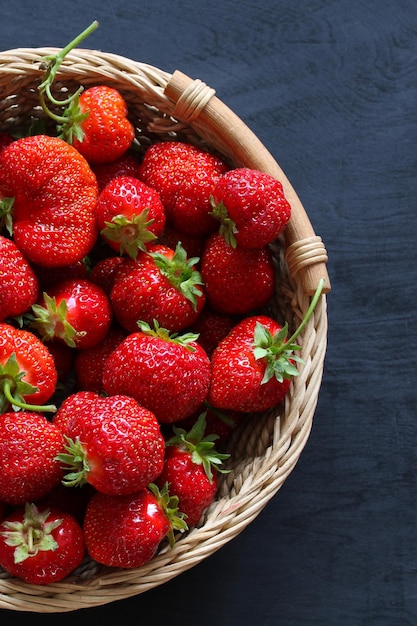 Reife Erdbeeren in einem Korb auf schwarzem Holzhintergrund